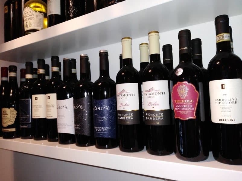 Floating white shelves lined with Italian red wine bottles